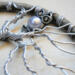 silver tree with twisted roots and branches inside a circular rustic frame, topped with a pearl-bodied owl charm.